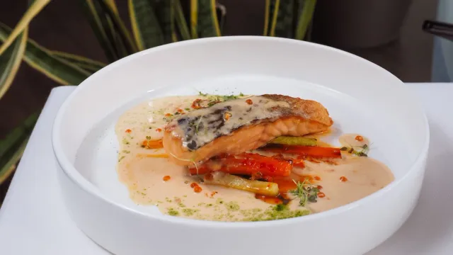 A plated fish dish with vegetables and sauce.