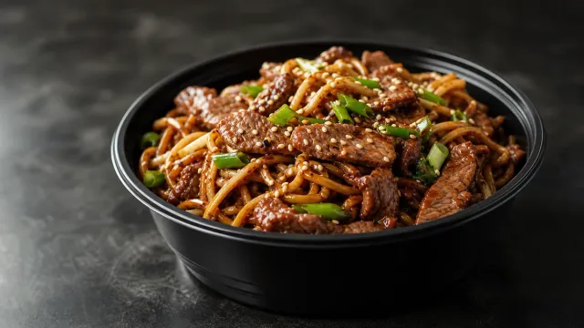 Stir-fried noodles in a dark bowl.