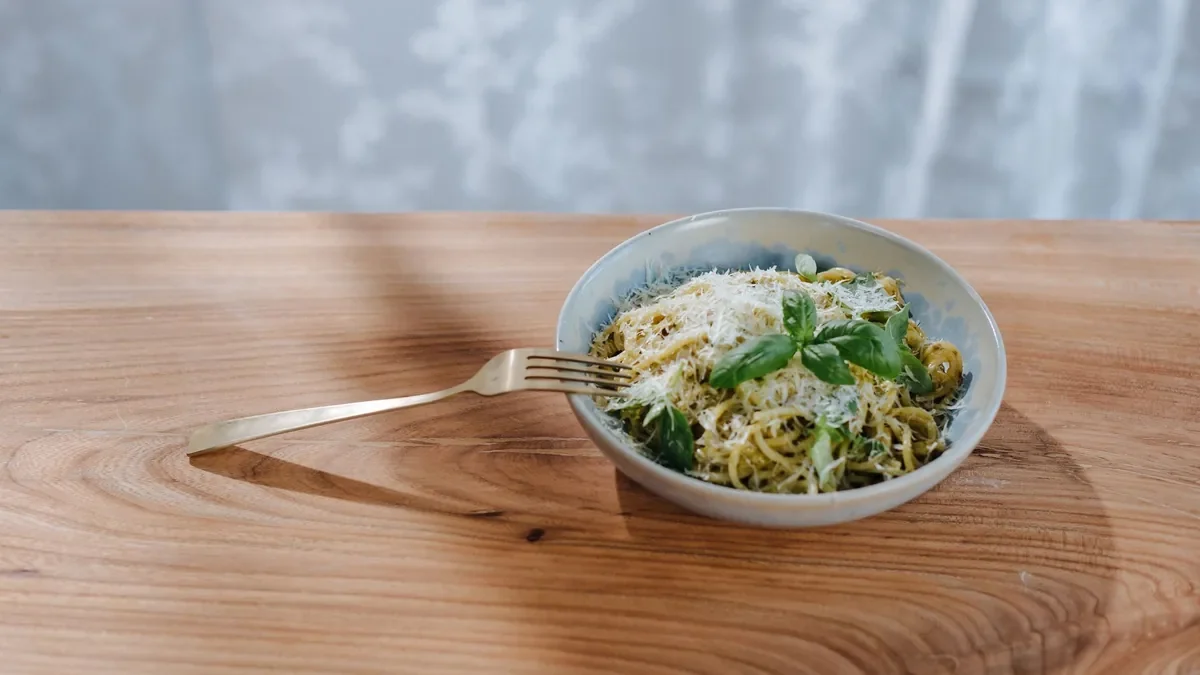 Pasta in a small bowl on a wooden table.