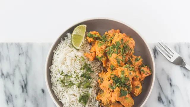 A rice dish with an orange sauce and fresh herbs.