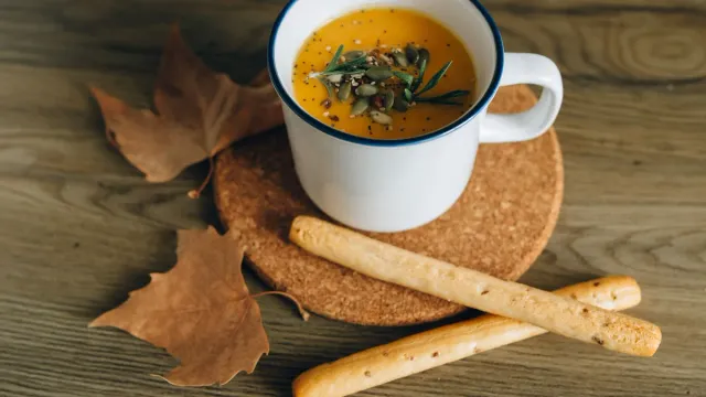 Orange soup in a cup beside bread.