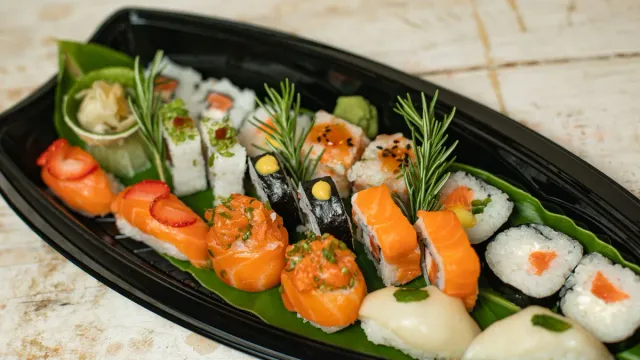 An assortment of sushi rolls on a black platter.
