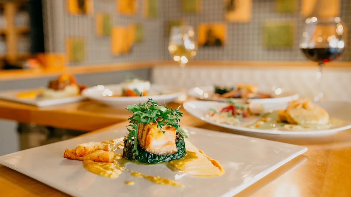 An elegantly plated pasta dish with fresh herbs and shaved cheese on a matte ceramic plate, soft window light from the left at a 45-degree angle.