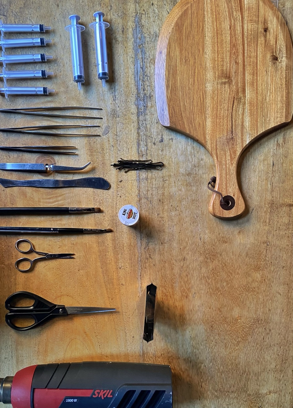 A restaurant food-styling kit laid out for a menu photoshoot &mdash; tweezers, brushes, scissors, board, and a heat gun